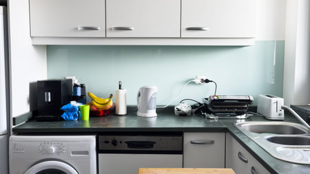 A kitchen with a green color theme. The kitchen has a black stove and a white sink. There are many cabinets and drawers in the kitchenの写真素材