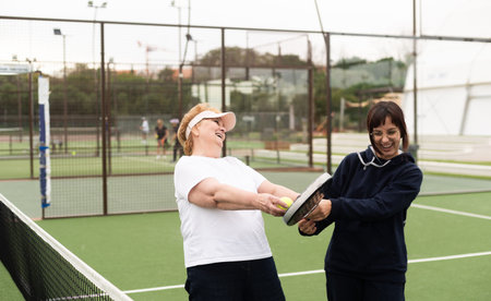 a girl teaches her grandmother how to play padelの写真素材