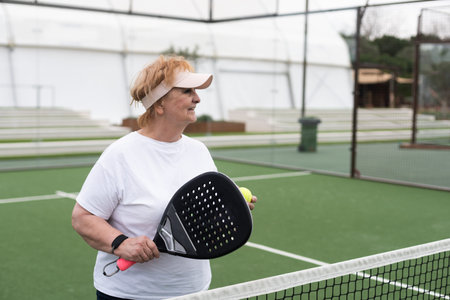 Padel, sports and portrait of senior woman on court for game, match and training for challenge. Indoor, smile and person with racket for workout, exercise and fitness for tennis, practice and hobbyの写真素材