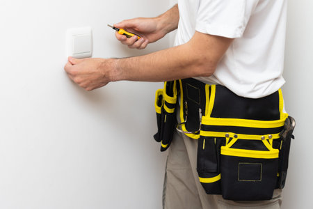 Electrician installs lighting switch in the wall