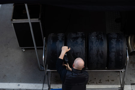 Mechanic performs automotive maintenance on red race car wheel and tire. focused pit stop service...