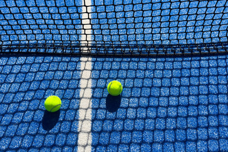 paddle tennis ball near the net on a blue paddle tennis court