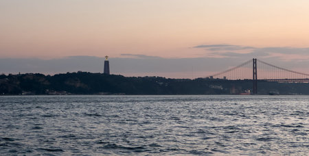 Iconic Red Suspension Bridge Spanning River Boats Clear Sky Lisbonの写真素材