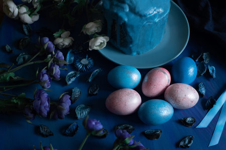 Easter painted eggs on a blue background with flowers and kulich blue and pinkish-red with silver