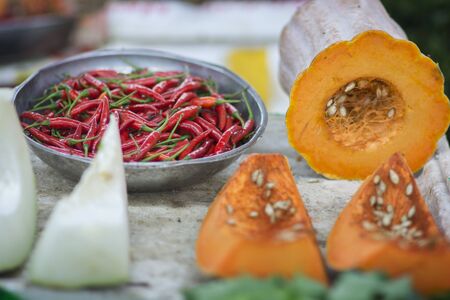 Red chilli peppers in a metal bowl, next to a sliced (Cucurbita moschata)の写真素材