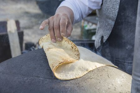 Man baking a traditional Druze Pita bread, on a Saj or Tavaの写真素材
