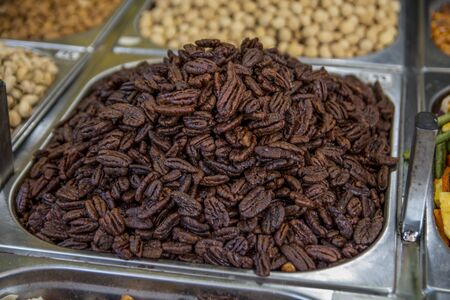 A pile of traditional caramelized, roasted, sweet Pecan nuts, inside a metal can, in the Mahane...