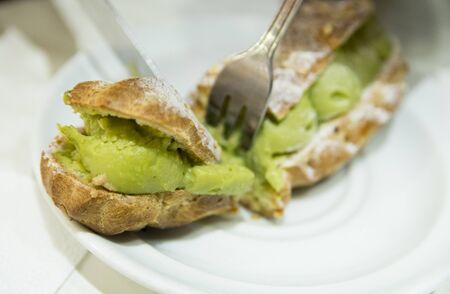 Top view close up of pistachio eclair, traditional French dessert, over a white plate, Strasbourg, Alsace, France.の写真素材