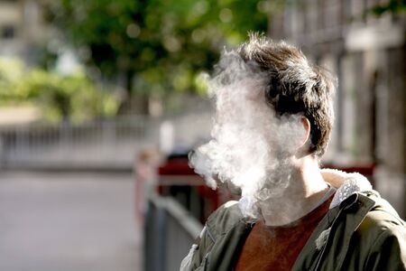 A man's face completely covered by thick cigarette smoke