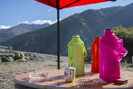 Colorful plastic tea kettles, in colors of Green, Red and Pink, outdoors on a table