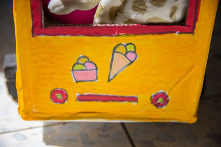 Rear part of an homemade bus for kids, made of cardboard, painted yellow with a painting of Ice...