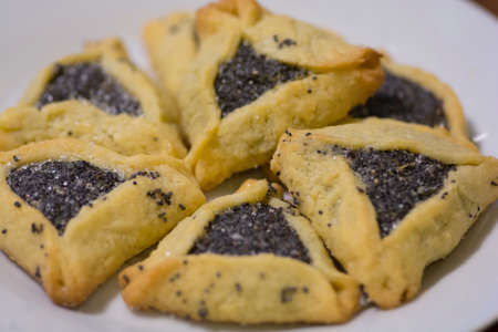 Close up of "Haman pockets", also known as Hamantashen, an Ashkenazi Jewish triangular filled-pocket cookies, usually associated with the Jewish holiday of Purim, filled with sweet poppy seedsの写真素材