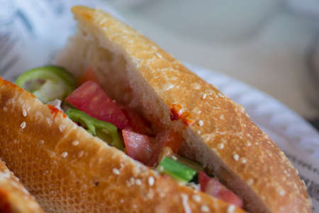 Close up of a Tunisian sandwich, usually containing oil-packed tuna, hard boiled egg, potatoes, olives or pickles, preserved lemon, and harissa pasteの写真素材