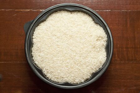 Rice grain uncooked in flower shape bowl on wooden boardの写真素材