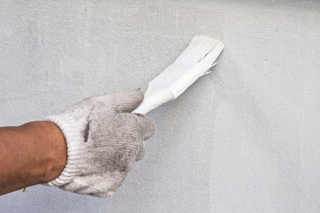 Hand hodling paint brush against the wallの写真素材