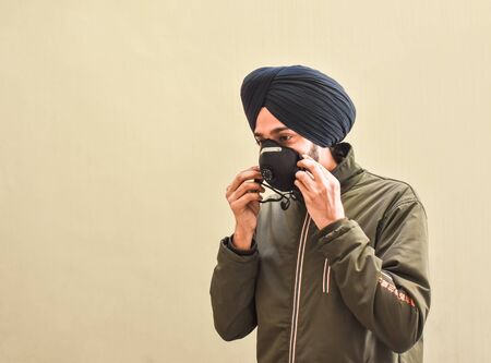 portrait image of a Indian Sikh boy wearing a face mask that protects against the spread of corona virus disease.の写真素材