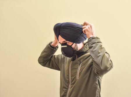 portrait image of a Indian Sikh boy wearing a face mask that protects against the spread of corona virus disease.の写真素材