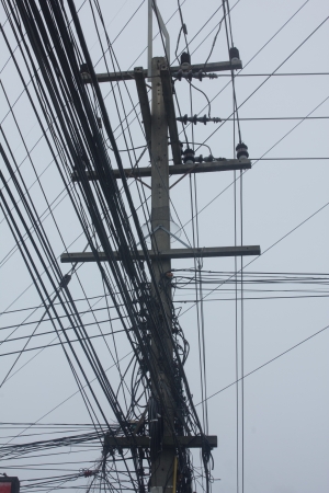 Stock Photo - messy old electricity post by the road with power line cables, transformers and phone lines  blue sky background の写真素材