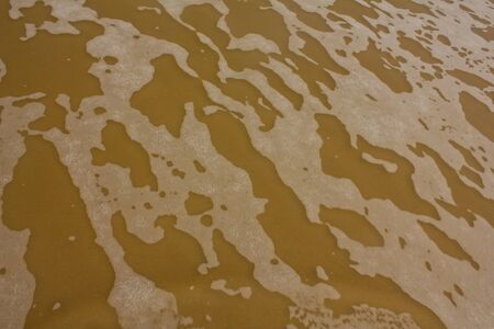 Stock Photo - Closeup detail of the foaming sea waves washing ashore at the beach.の写真素材