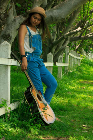 beautiful young country girl with a guitar on the woodsの写真素材
