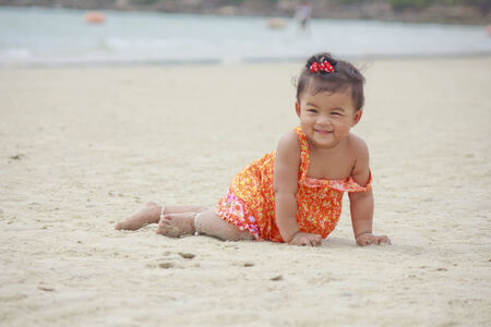 Baby girl playing in the sand on the beach Ocean as background Stock Photoの写真素材