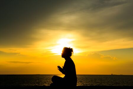 Silhouette of a woman against the sky at sunsetの写真素材