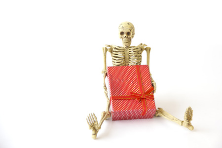 Human skeleton Sit on the floor with gift box on white backgroundの写真素材