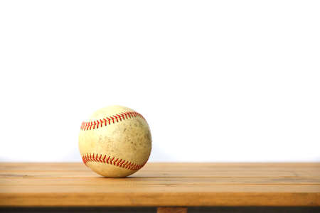 dirty old baseball lying on a wooden tableの写真素材