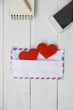 On a white wooden table composition for Valentine's Day, heart tissue in an envelope, a letter, a...