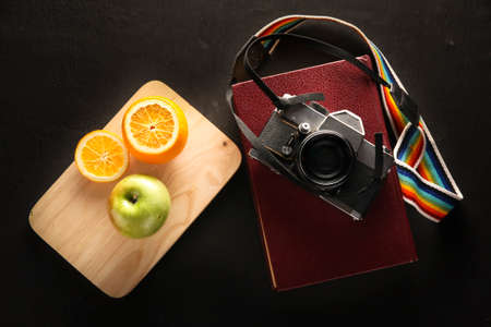 Old Camera Closeup on old Books with fruit on Black Background