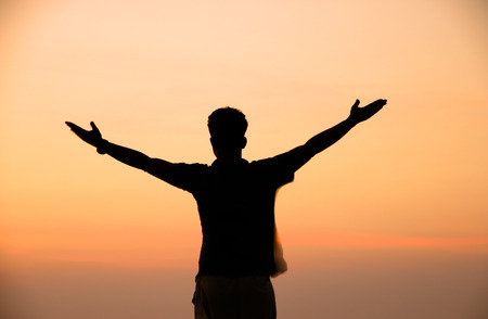 Silhouette of man on top of mountain at sunsetの写真素材