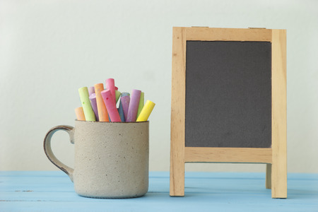 empty blackboard and colored chalks on wooden table vintage effect style pictures