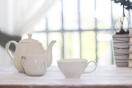 Little white tea cup and a kettle isolated over side windows backgroundの写真素材