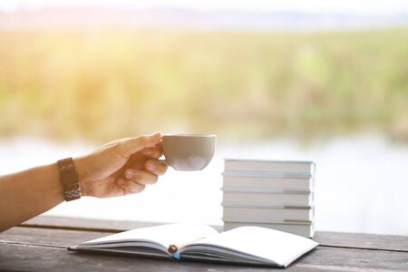 Hand holding a cup of coffee or tea in the morning light.の写真素材