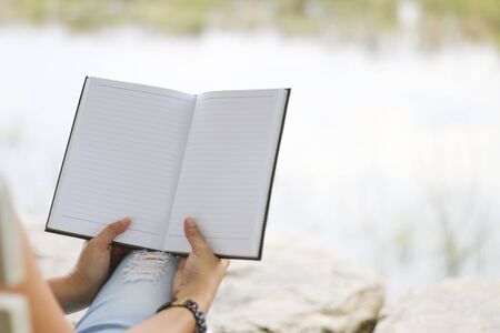 Young woman reading finance graph sheet under sunlight at gardenの写真素材