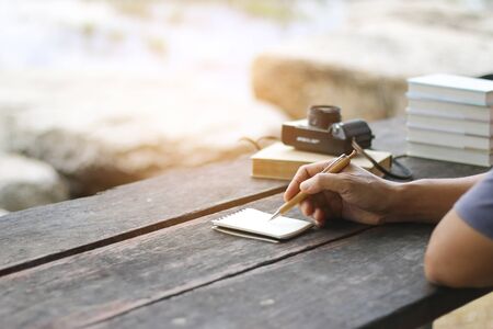 Young business man writing at the notebook outside office table work space,close up and selective focusの写真素材