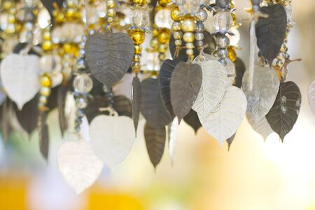 Several golden Pho tree leave are hanging for decoration.Pho silver backgroundand goldの写真素材