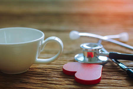 Empty white cup with wooden heart on wooden tableの写真素材