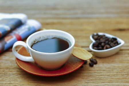 cup of good hot coffee and a newspaper on a wooden tableの写真素材