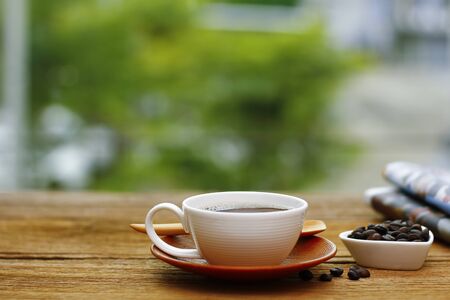 cup of good hot coffee and a newspaper on a wooden tableの写真素材