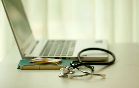 A medical stethoscope and norebook on a white tableの写真素材