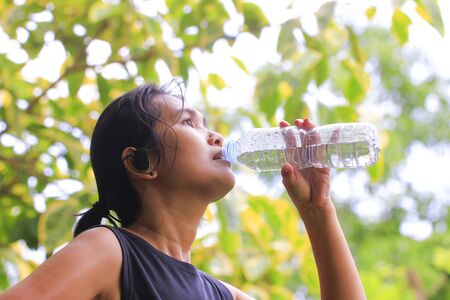 beautiful athletic girl drinking water after exercisingの写真素材