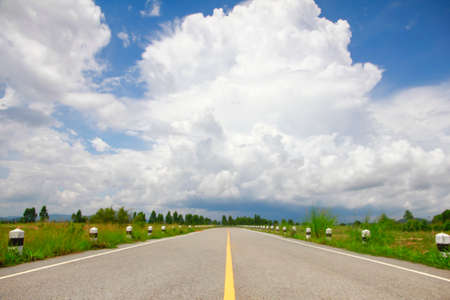 Empty country road with cloudy sky and sunlightの写真素材