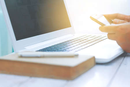 Blurry man working from home using smart phone and laptop computer