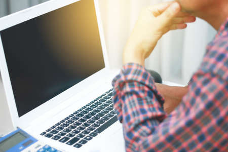 Blurry designer hand working laptop with foreground on wooden deskの写真素材