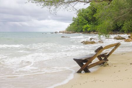 Beach chairs on perfect tropical yellow sand beach with blue sea and island on backgroundの写真素材