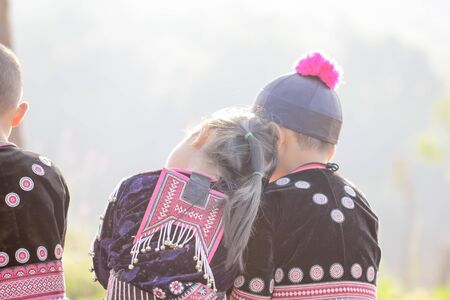 Lovely boy and girl playing outdoors while posing wearing ethnic clothes from the Hmong tribe, indigenous people of Thailand.の写真素材