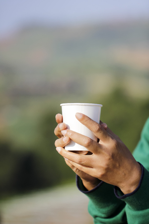 Human hand holding a white cup of coffeeの写真素材