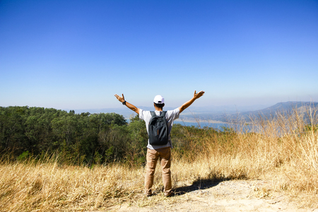 Adventurous man is standing on top of the mountain and enjoying the beautiful viewの写真素材