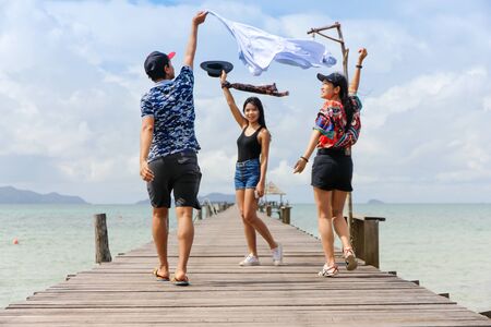 KOH MAK,THAILAND AUGUST 26,2017:Joyful multiracial group of friends walking on the wooden bridge have fun and laughing togetherのeditorial素材